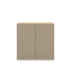 Vor weißem Hintergrund sieht man ein steingraues Sideboard mit zwei Drehtüren. Die Türen haben keine Griffe und sind mit einem Push-to-open-Mechanismus ausgestattet. Auf dem Schrank ist eine Abdeckplatte aus Eichenholz angebracht.