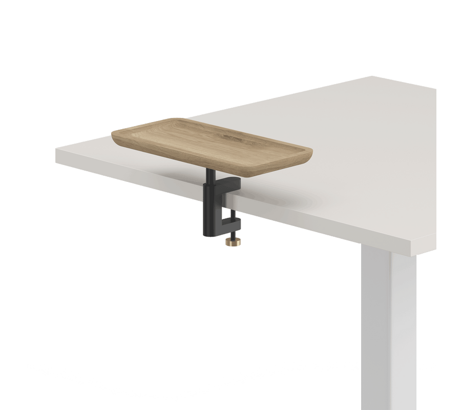 Ein Anschnitt eines weißen quadratischen Tisches mit angeschraubtem Anbautablet ist zu sehen. Das Anbautablet ist rechteckig, besteht aus Bambus und ist mit einer schwarzen Multiklemme am Tisch befestigt.